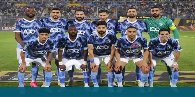 لاعبو فريق بيراميدز يحتفلون بالفوز بكأس أفريقيا، مع شعار البطولة في الخلفية.